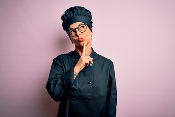 Middle age brunette chef woman wearing cooker uniform and hat over isolated pink background Thinking concentrated about doubt with finger on chin and looking up wondering