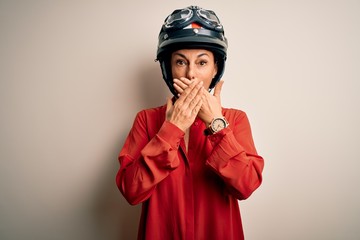 Middle age motorcyclist woman wearing motorcycle helmet over isolated white background shocked covering mouth with hands for mistake. Secret concept.