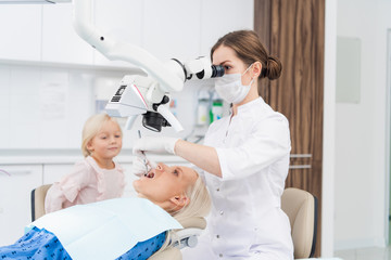 A female dentist examines the oral cavity of her patient on the dentist's chair