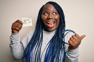 Young african american plus size woman with braids holding reminder paper with yes message pointing...