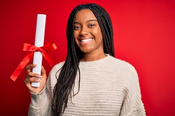 Young african american student girl holding university diploma over red isolated background with a happy face standing and smiling with a confident smile showing teeth