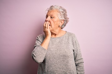 Senior beautiful woman wearing casual t-shirt standing over isolated pink background bored yawning tired covering mouth with hand. Restless and sleepiness.
