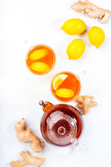 Healing black herbal tea with ginger, honey, lemon and mint. Immune booster drink in glass cup on white kitchen table background with copy space. Top view