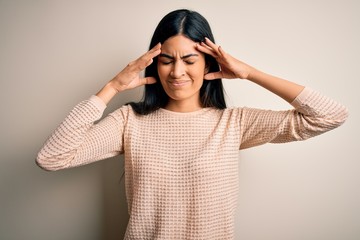 Young beautiful hispanic woman wearing elegant pink sweater over isolated background with hand on head for pain in head because stress. Suffering migraine.