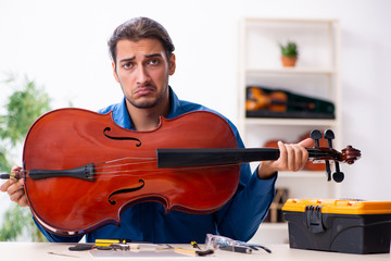 Young male repairman repairing cello