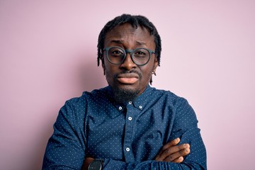Fototapeta premium Young handsome african american man wearing casual shirt and glasses over pink background skeptic and nervous, disapproving expression on face with crossed arms. Negative person.