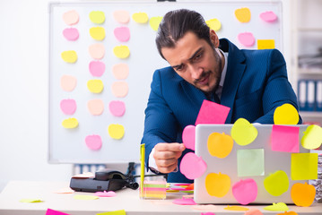 Young male employee in conflicting priorities concept
