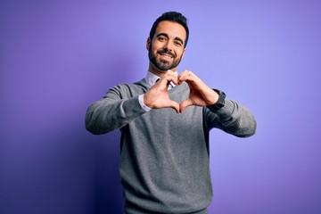 Handsome businessman with beard wearing casual tie standing over purple background smiling in love doing heart symbol shape with hands. Romantic concept.
