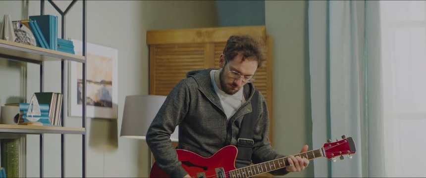 DX MED Caucasian male playing his electric guitar at home, practicing during quarantine. Shot on RED Helium in 8K with Atlas Orion 2x Anamorphic lens