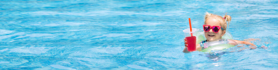 Beautiful little girl, cute toddler with blonde hair in swimwear swims in swimming pool and...