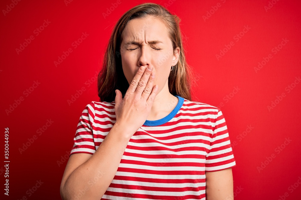 Poster young beautiful blonde woman wearing casual striped t-shirt over isolated red background bored yawni