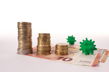 A few piles of stacked coins decrease in size due to the appearance of the covid-19 coronavirus. Conceptual image about the economic crisis.