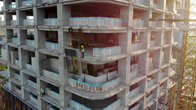 Workers are Installing the Precast Glass Panel on The Construction Site. Cladding of the Building by Curtain Walls.