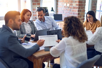 Group of business workers working together. Sitting on desk using laptop reading documents at the office