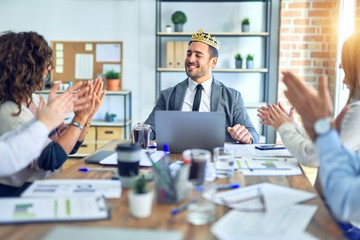 Group of business workers smiling happy and confident. Working together with smile on face applauding one of them wearing king crown at the office