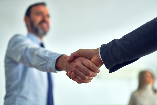 Business workers standing together shaking hands at the office