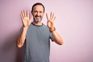 Middle age hoary man wearing casual striped t-shirt standing over isolated pink background showing...