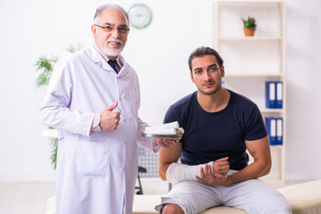 Obraz premium Young injured man visiting experienced male doctor traumatologis