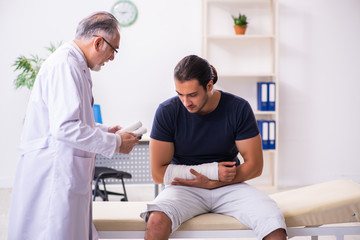 Young injured man visiting experienced male doctor traumatologis