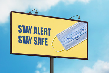 Stay Alert Stay Safe warning sign with smiling face mask on blue sky background. Large billboard with the message text. Staying alert after coronavirus lockdown, end of Covid-19 quarantine concept - obrazy, fototapety, plakaty