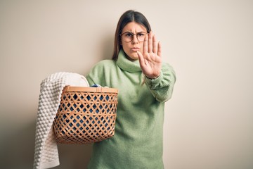 Young beautiful woman wearing casual sweater standing over isolated white background with open hand doing stop sign with serious and confident expression, defense gesture