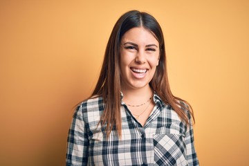 Young beautiful woman wearing casual shirt standing over isolated orange background with a happy and cool smile on face. Lucky person.