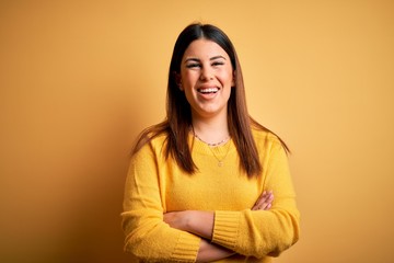 Young beautiful woman wearing casual sweater over yellow isolated background happy face smiling with crossed arms looking at the camera. Positive person.