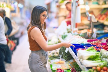 Young beautiful woman smiling happy and confident. Standing with smile on face buying food at supermarket