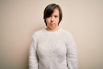 Young down syndrome woman standing over isolated background depressed and worry for distress,...