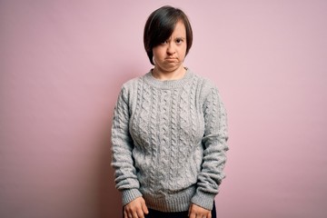 Young down syndrome woman wearing casual sweater over isolated background depressed and worry for distress, crying angry and afraid. Sad expression.
