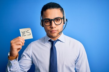 Young brazilian call center agent man holding reminder paper with yes message with a confident...