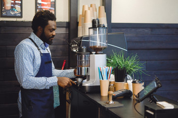 Bearded African American in an apron in a coffee shop.