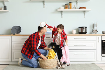 Man and his little son having fun while doing laundry at home
