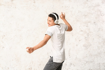 African-American teenager dancing and listening to music against light background