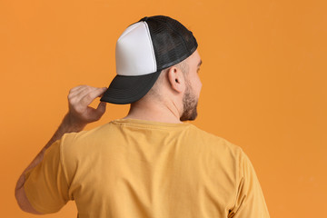 Handsome man in stylish cap on color background