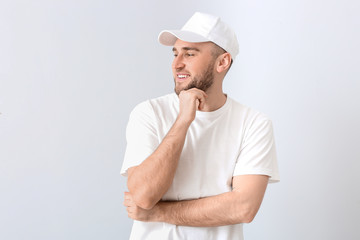 Handsome man in stylish cap on light background