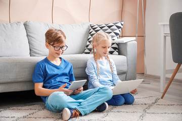 Cute little children with laptop and tablet at home. Concept of online education