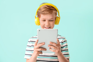 Cute little boy with tablet computer on color background. Concept of online education
