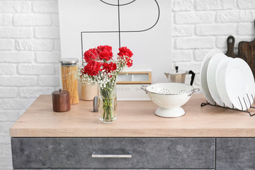 Vase with bouquet of beautiful flowers on table in kitchen
