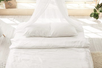 Big comfortable bed with clean linen in room © Pixel-Shot