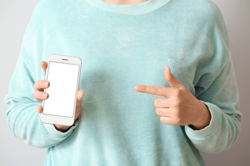 Woman with mobile phone on light background