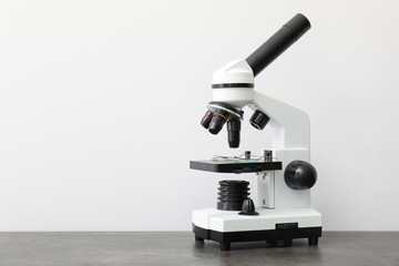 Modern microscope on table against light background