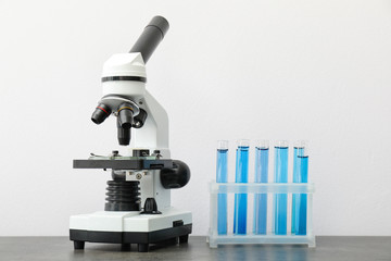 Modern microscope and test tubes on table