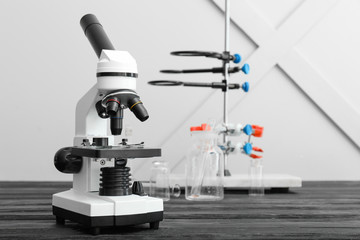 Modern microscope and laboratory glassware on table