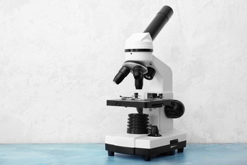 Modern microscope on table against light background