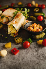 mexican food background of chicken and cheese burritos with vegetable on stone plate in dark tone, selective focused