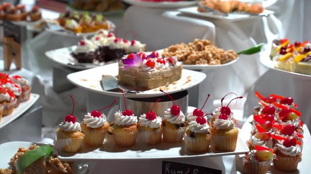 Panning shot of various desserts in plates on display at counter in hotel, closeup of fresh sweet food during buffet at restaurant - Montego Bay, Jamaica