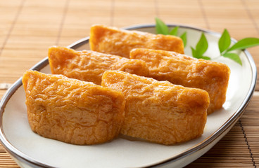 Japanese Inari Sushi on a plate set against a wooden backdrop
