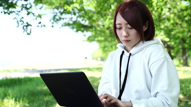パソコンを操作する女性　屋外　緑