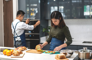 Young asian family couple having fun cooking together with fresh vegetable salad on table.Happy couple looking to prepare the yummy eating lunch in kitchen